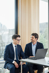 Two businessmen with laptop talking in office - CHAF001768