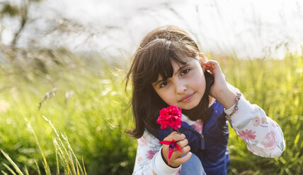 Porträt eines kleinen Mädchens mit roter Blume in der Natur - MGOF001931