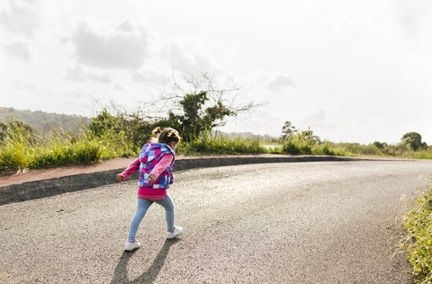Rückenansicht eines kleinen Mädchens auf der Landstraße, lizenzfreies Stockfoto