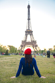 Frankreich, Paris, Champ de Mars, Rückenansicht einer auf einer Wiese sitzenden Frau mit Blick auf den Eiffelturm - GEMF000921