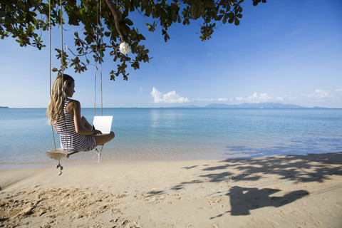 Thailand, Frau benutzt Laptop am Strand, lizenzfreies Stockfoto