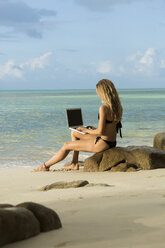 Thailand, woman using laptop on beach - SBOF000003
