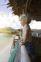 Thailand, Kleinkind in einer Hütte am Strand, das in die Ferne schaut - SBOF000031