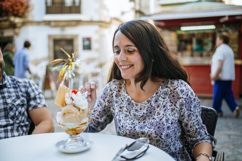 Frau isst Eiscreme in einem Straßencafé - KIJF000405