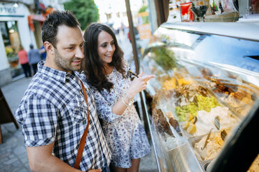 Couple choosing ice cream in an ice cream shop showcase - KIJF000409