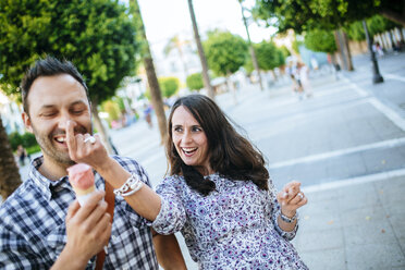 Couple having fun while eating an ice cream cone - KIJF000412