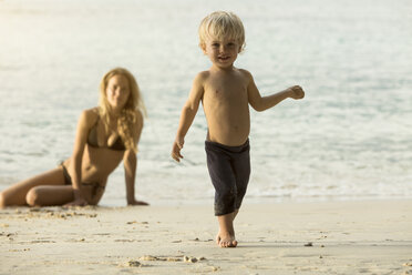 Thailand, glücklicher Junge am Strand mit Mutter im Hintergrund - SBOF000038