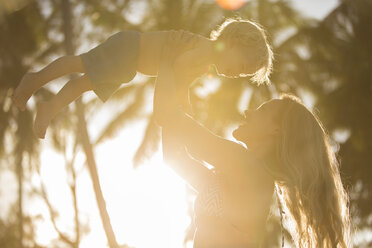 Happy mother lifting up her son in backlight - SBOF000042