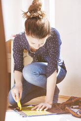 Young woman cutting fabric on the floor at home - SEGF000575