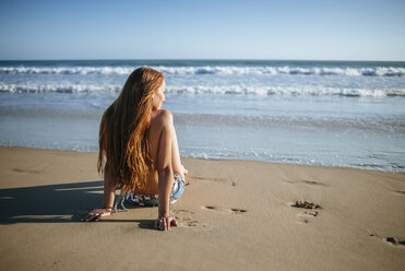 Junge Frau sitzt am Strand - KIJF000421