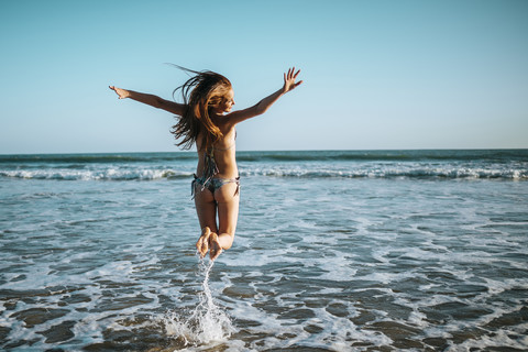 Enthusiastic young woman jumping on beach stock photo