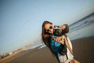 Junge Frau beim Fotografieren am Strand - KIJF000428