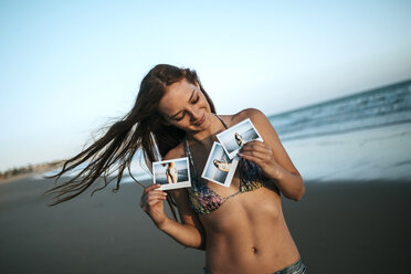Junge Frau zeigt Sofortbilder am Strand - KIJF000430