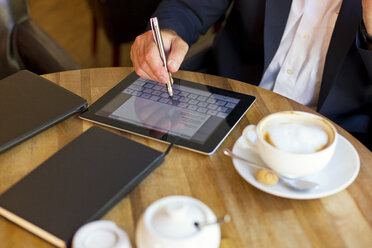 Geschäftsmann sitzt in einem Café und benutzt ein digitales Tablet, Teilansicht - MAEF011824