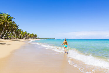 Dominican Rebublic, Young woman walking along tropical beach - HSIF000454