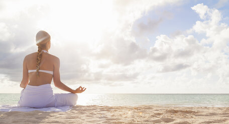 Dominikanische Republik, Junge Frau bei Yoga-Übungen mit Blick auf einen tropischen Strand - HSIF000475