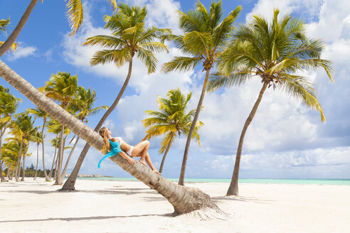 Dominikanische Republik, Junge Frau entspannt sich auf einer Palme mit Blick auf einen tropischen Strand - HSIF000476
