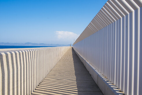 Spanien, Andalusien, Tarifa, Licht und Schatten durch einen Zaun auf einer Betonfläche - KIJF000436