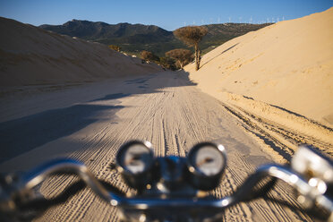 Spanien, Andalusien, Tarifa, Punta Paloma, Moto auf einer Straße zwischen Dünen, mit Sand bedeckt - KIJF000450
