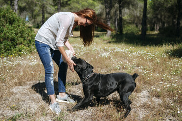 Junge Frau spielt mit ihrem Hund mit einem Ball - KIJF000471