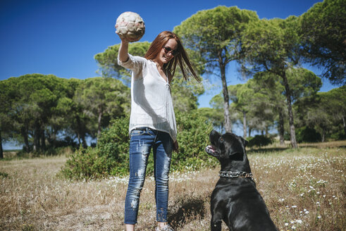 Junge Frau spielt mit ihrem Hund mit einem Ball - KIJF000472