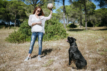 Junge Frau spielt mit ihrem Hund mit einem Ball - KIJF000474