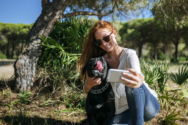 Lächelnde junge Frau macht ein Selfie mit ihrem Hund - KIJF000477