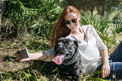 Lächelnde junge Frau macht ein Selfie mit ihrem Hund - KIJF000478