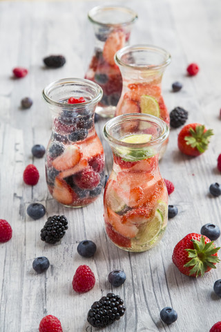 Glasflaschen mit Entgiftungswasser, das mit verschiedenen Früchten angereichert ist, lizenzfreies Stockfoto