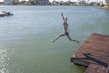 South Africa, Cape Town, girl jumping in water from jetty - ZEF008716