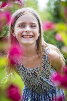 Porträt eines glücklichen Mädchens mit Zahnlücke im Garten - SARF002775