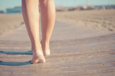 Legs of woman walking on boardwalk at the beach - SIPF000555
