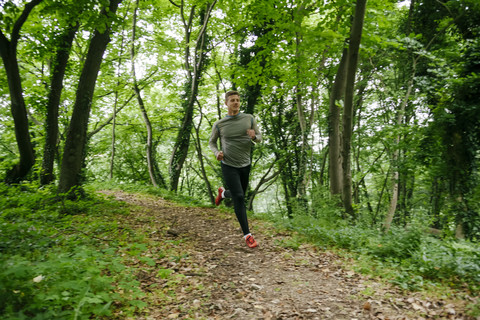 Junger Mann läuft im Wald, lizenzfreies Stockfoto