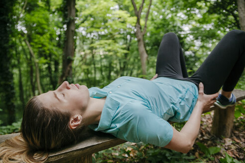 Junge Frau entspannt sich auf einer Bank im Wald - ZEDF000203