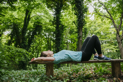 Junge Frau entspannt sich auf einer Bank im Wald - ZEDF000205
