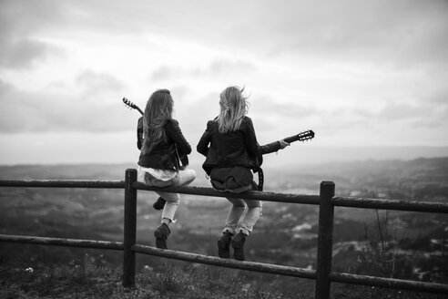 Zwei Frauen sitzen mit Gitarren auf einem Holzzaun - JPF000160