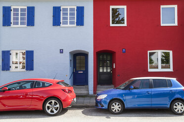 Ein rotes und ein blaues Auto parken vor einem blauen und einem roten Haus - TCF004971