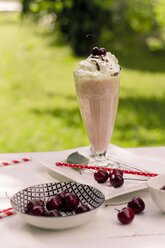 Zwei Gläser Vanillemilchshake mit Vanilleeis, Sahne und Schokoladensauce, Kirschen in der Schale - YFF000549