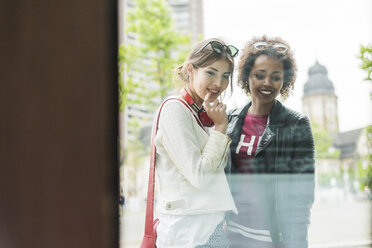 Two young women looking in shop window - UUF007649