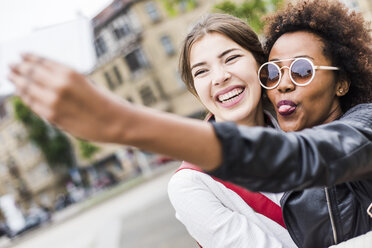 Porträt von zwei glücklichen besten Freunden, die ein Selfie mit einem Smartphone machen - UUF007658