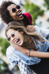 Laughing woman giving her friend a piggyback ride - UUF007677