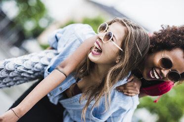 Laughing woman giving her friend a piggyback ride - UUF007678