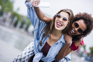 Porträt von zwei glücklichen besten Freunden, die ein Selfie mit einem Smartphone machen - UUF007679