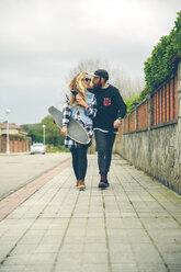 Verliebtes Paar mit Skateboard auf dem Bürgersteig - DAPF000120