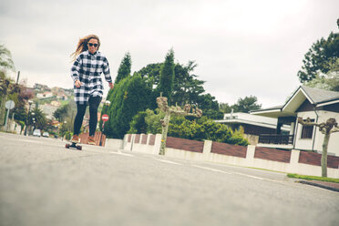 Junge Frau, die auf der Straße Skateboard fährt - DAPF000124