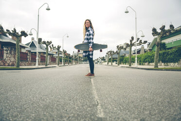 Lächelnde junge Frau mit Skateboard auf der Straße - DAPF000129
