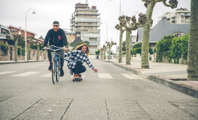 Glückliches Paar mit Fahrrad und Skateboard auf der Straße - DAPF000132