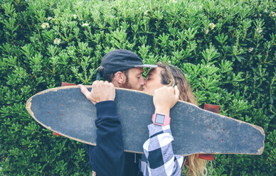 Paar küsst sich hinter Skateboard - DAPF000134