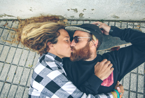 Couple lying on skateboard kissing stock photo