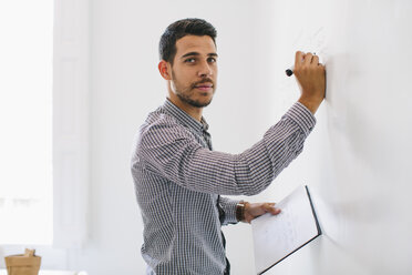 Man in office writing chart on wall - EBSF001439